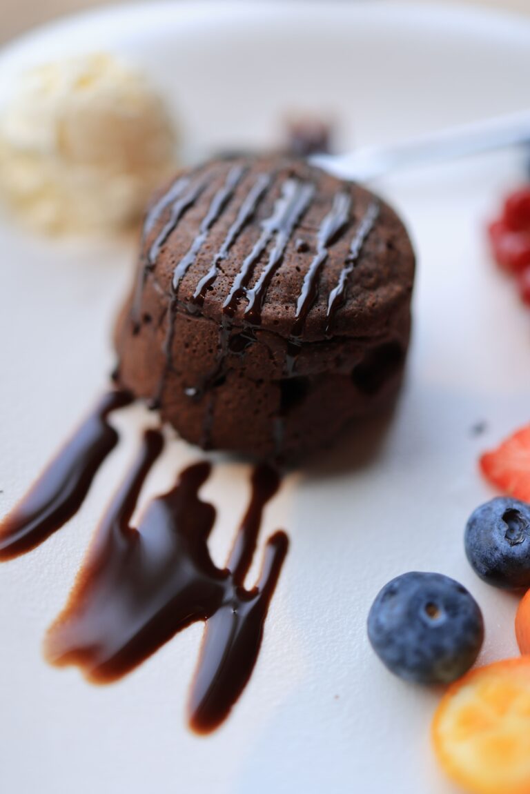 Close-up of a chocolate lava cake with fresh berries and vanilla ice cream, captured indoors.