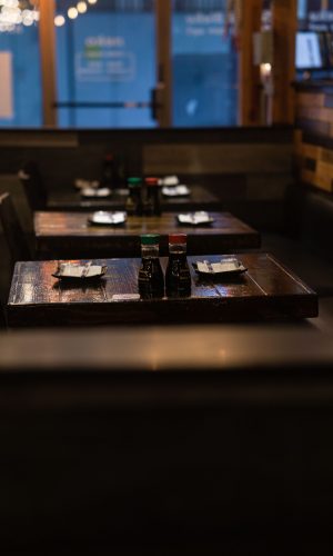 Warm and inviting restaurant interior featuring wooden tables set with condiments and plates.